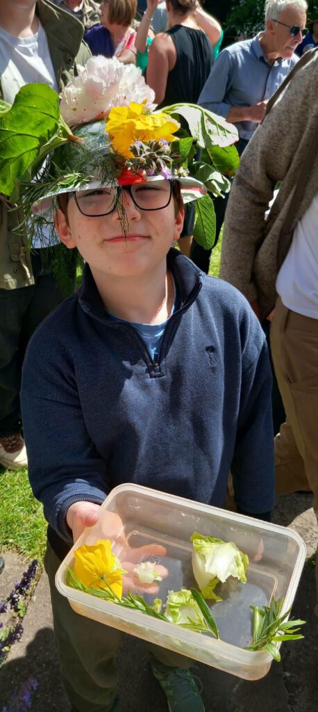 young boy showing the camera a selection of flowers and leaves to the camera